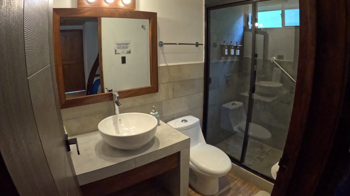 Baño de habitación con lavamanos de sobreponer y ducha de vidrio